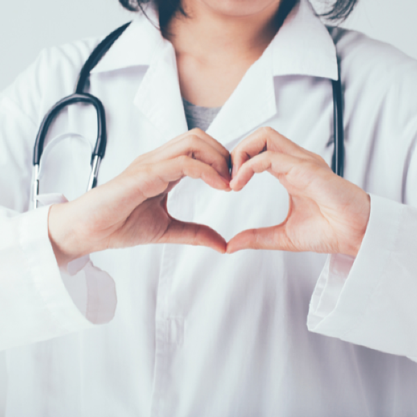 Person in a with coat with stethoscope, showing heart symbol with their hands